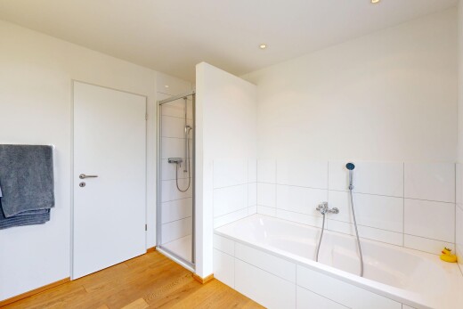 salle de bains avec cloison sèche, douche, sol en finition bois, salle de bain complète, et bain