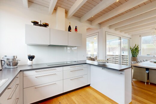 cuisine avec armoires blanches, plaque de cuisson, lumière naturelle, armoires à panneau plat, et plafond à poutres