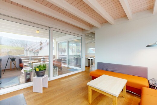 salon avec plafond en bois, sol en finition bois, plafond à poutres, lumière naturelle, et cloison sèche