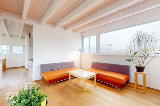 salon avec plafond à poutres, lumière naturelle, cloison sèche, sol en finition bois, et plinthes murales