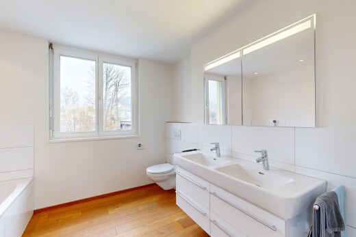salle de bains avec toilette, sol en finition bois, évier, salle de bain complète, et lumière naturelle