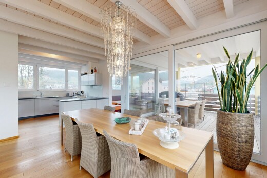 salle à manger avec plafond en bois, sol en finition bois, lumière naturelle, plafond à poutres, et lustre remarquable