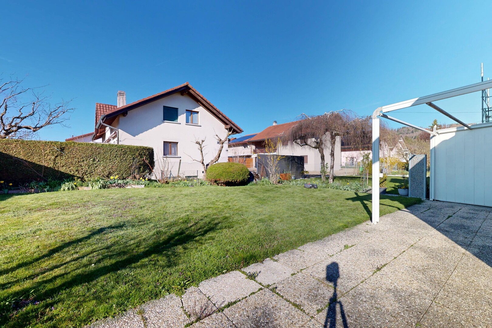 façade avec day time, cheminée, pelouse, property visible, et bardage en stuc