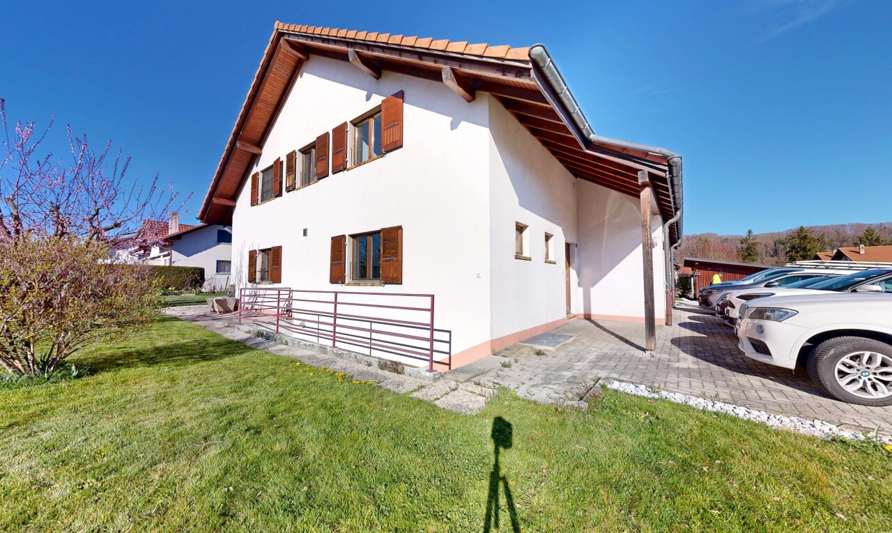 façade avec property visible, bardage en stuc, pelouse, aire de stationnement, et day time