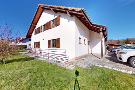 façade avec property visible, bardage en stuc, pelouse, aire de stationnement, et day time