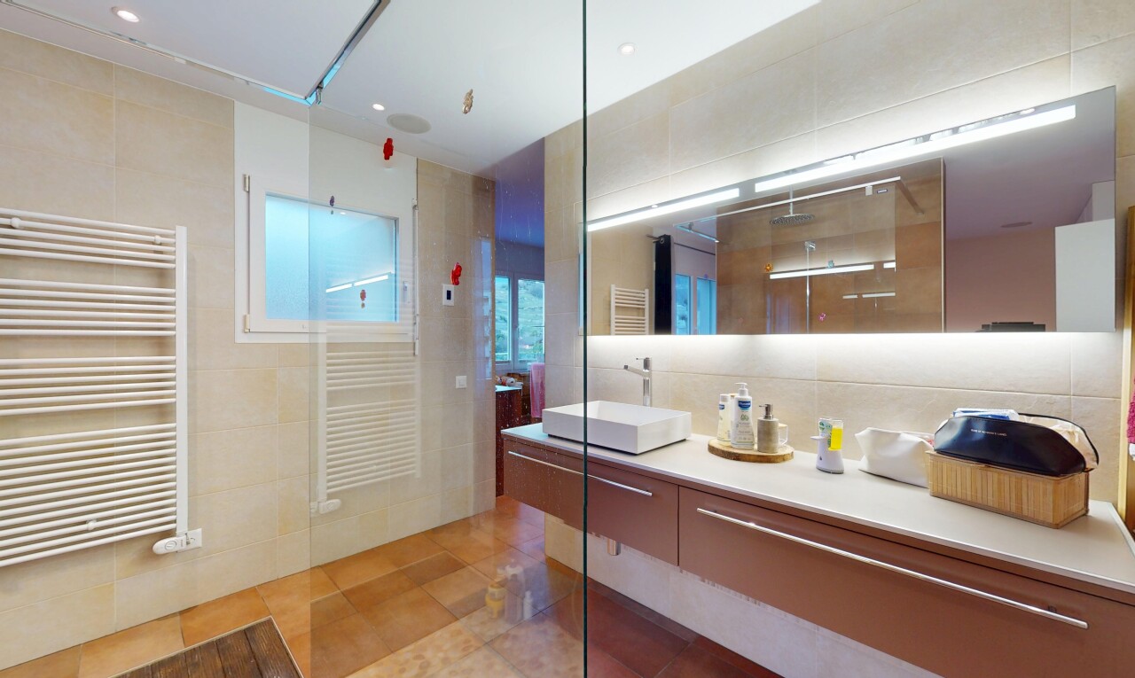 salle de bains avec évier, radiateur, chauffe-serviettes, douche, et mur en carrelage