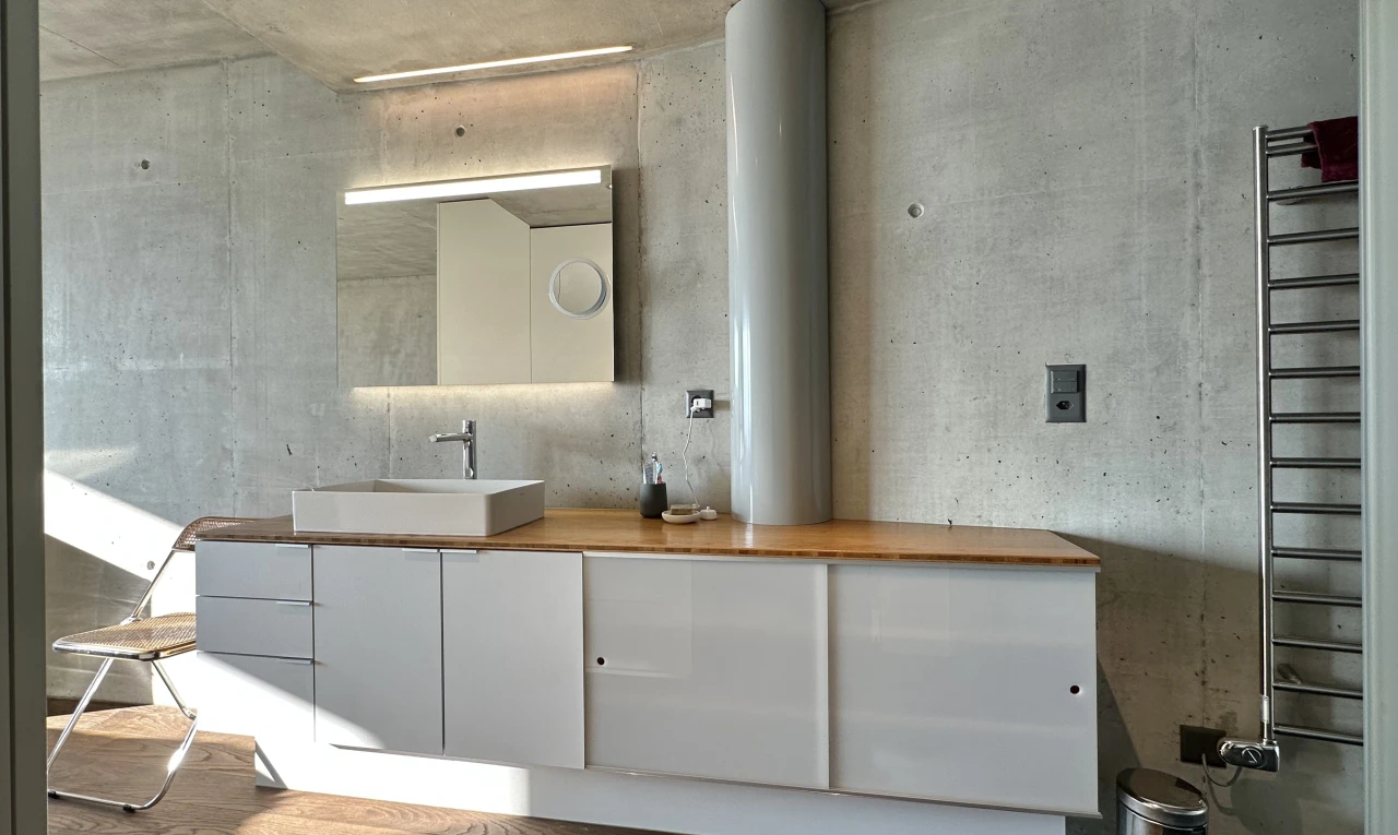 salle de bains avec mur en béton, vasque, plancher de bois, miroir, et meuble-lavabo