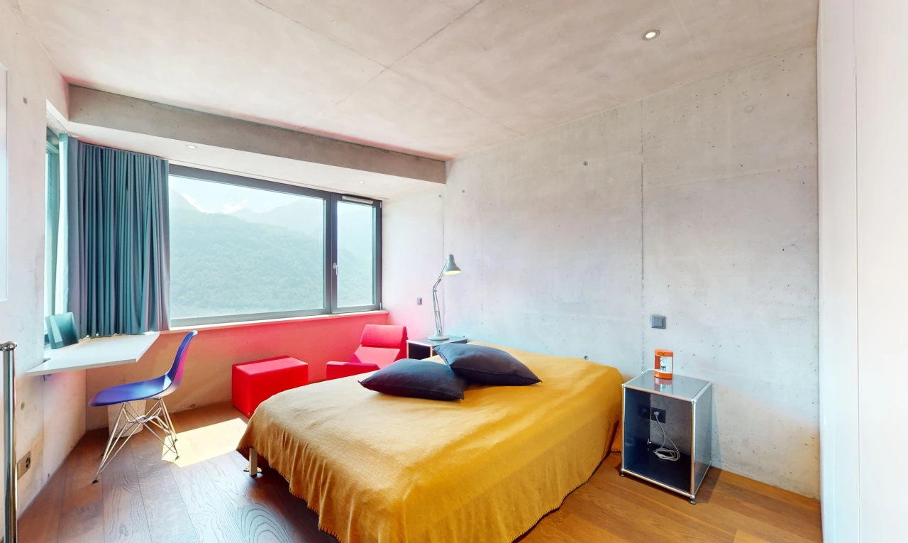 chambre avec plancher de bois, mur en béton, et lumière naturelle