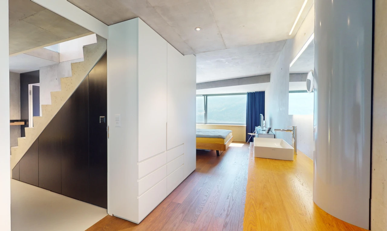 couloir avec plancher de bois, plafond en béton, et lumière naturelle
