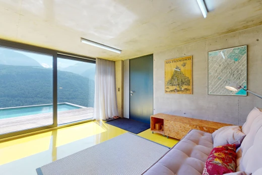 salon avec lumière naturelle, mur en béton, et vue sur la montagne