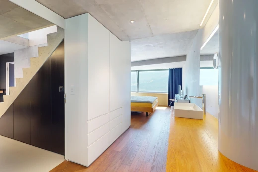 couloir avec plancher de bois, plafond en béton, et lumière naturelle