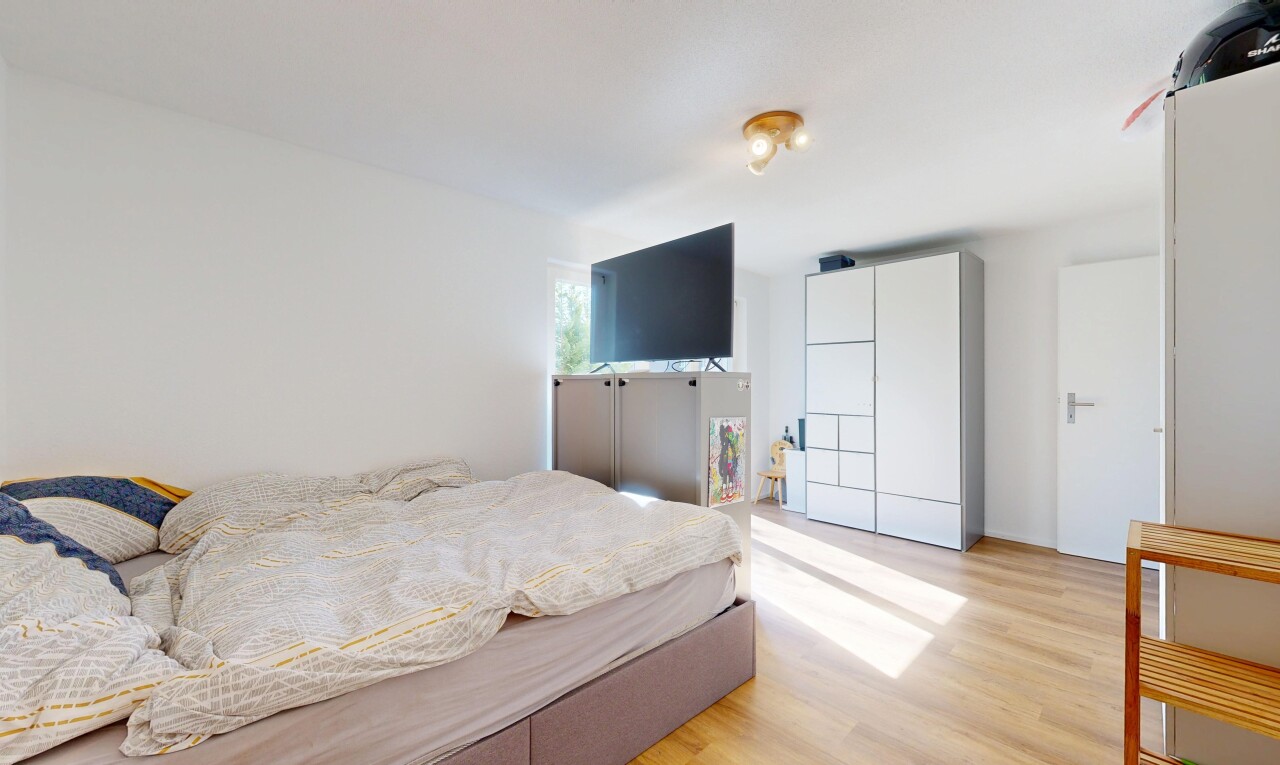 zimmer / schlafzimmer mit wood finish floor, holzfußboden, fernseher, drywall, und gipskartonwand