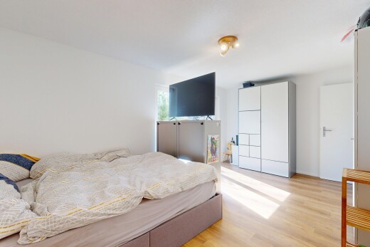 chambre avec wood finish floor, sol en finition bois, télévision, drywall, et cloison sèche
