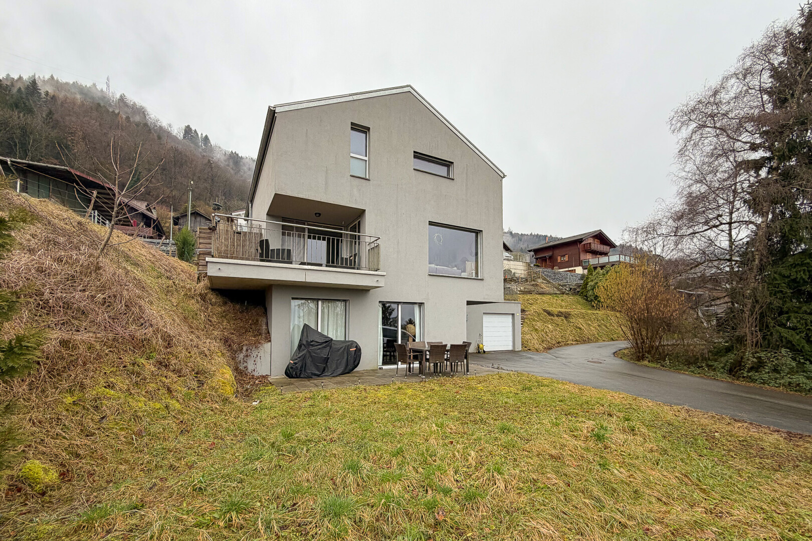 façade avec overcast, garage intégré, allée, balcon, et property visible