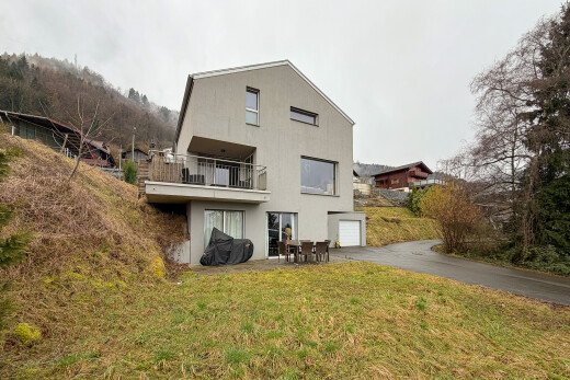façade avec overcast, garage intégré, allée, balcon, et property visible