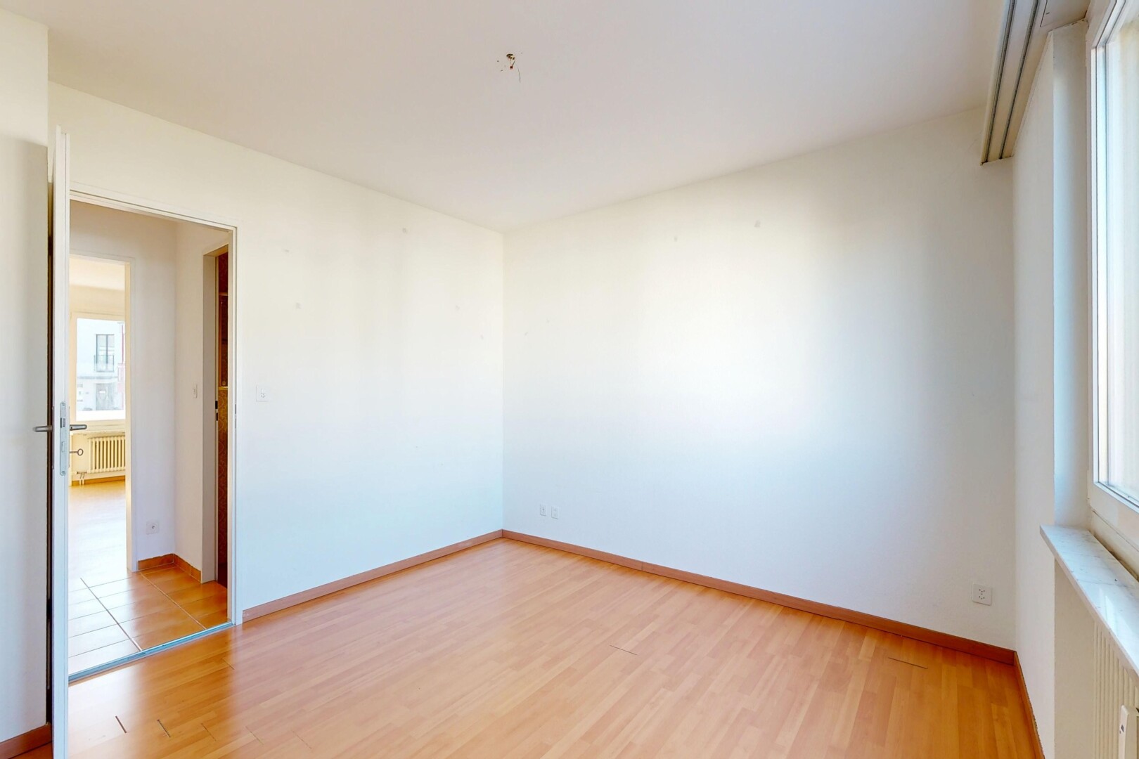 empty room with light wood-style flooring and radiator heating unit