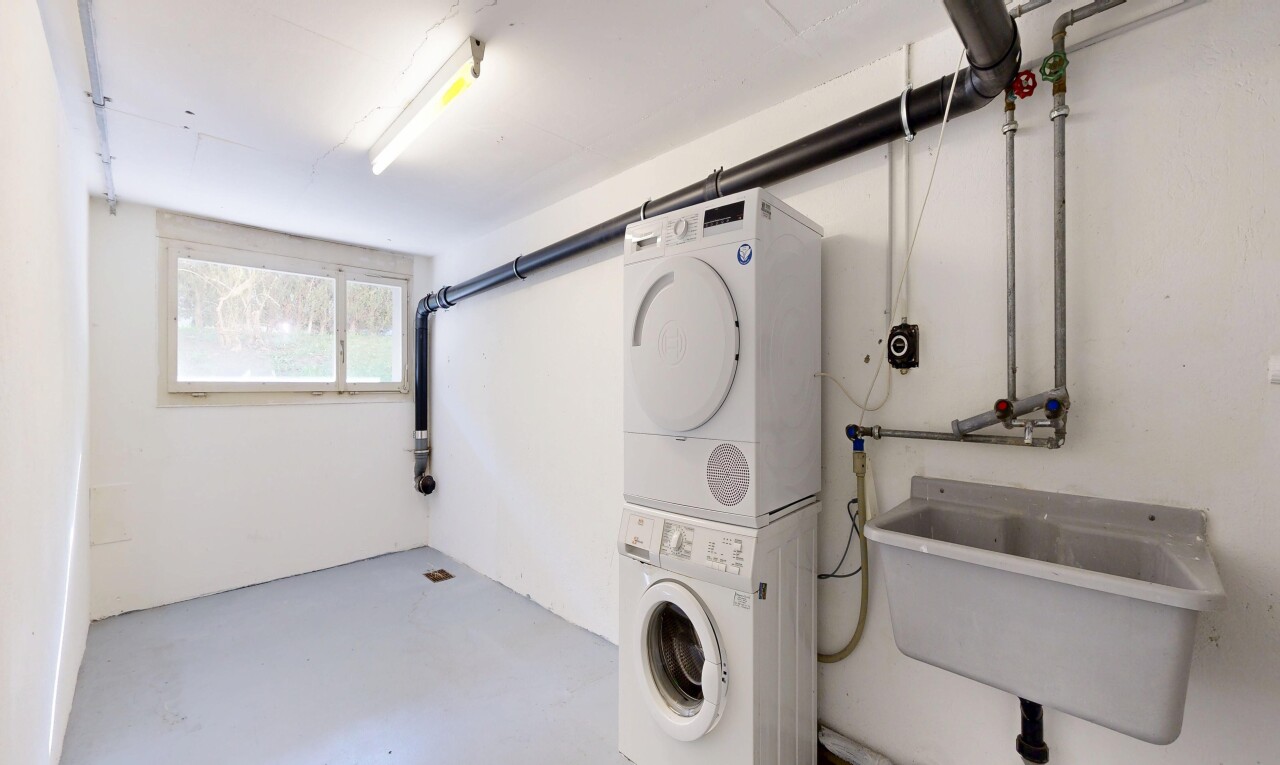laundry area featuring concrete floors and stacked washer / dryer