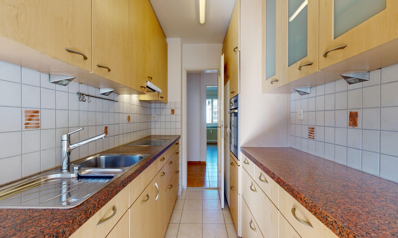 kitchen featuring dark countertops, glass insert cabinets, backsplash, and light wood finish cabinetry
