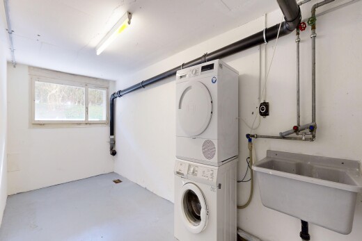 laundry area featuring concrete floors and stacked washer / dryer