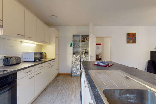 küche mit schwarzen geräten, weissen schränken und hellen fliesenböden