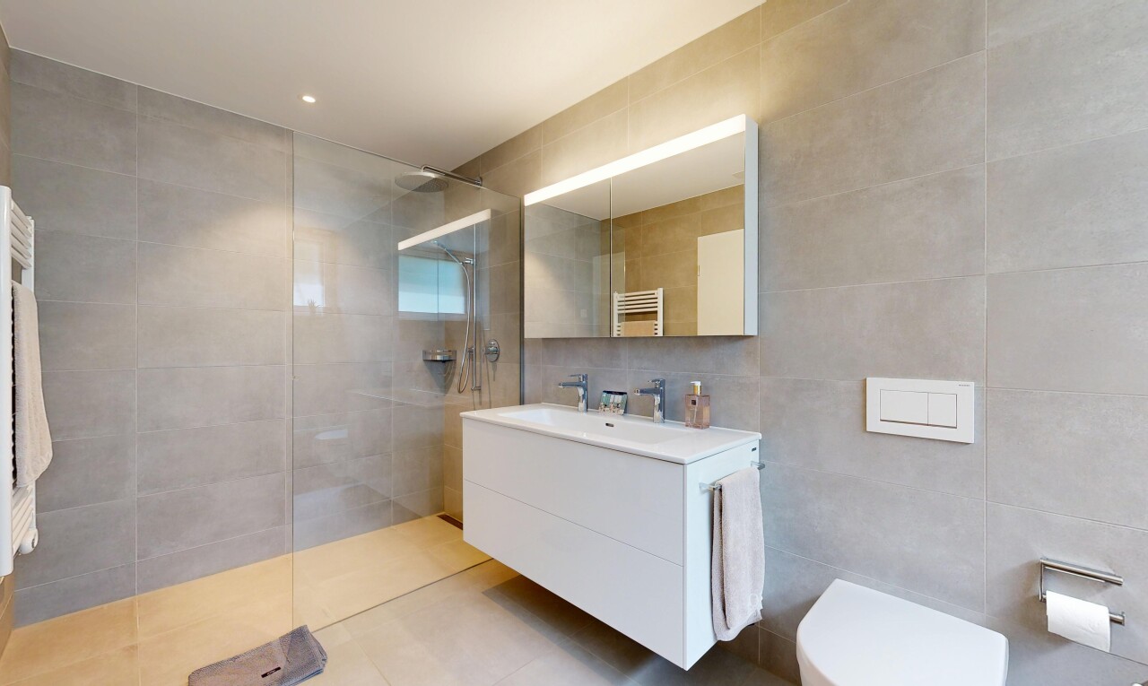 bathroom featuring a towel warming rack, tile walls, a walk in shower, vanity, and radiator heating unit