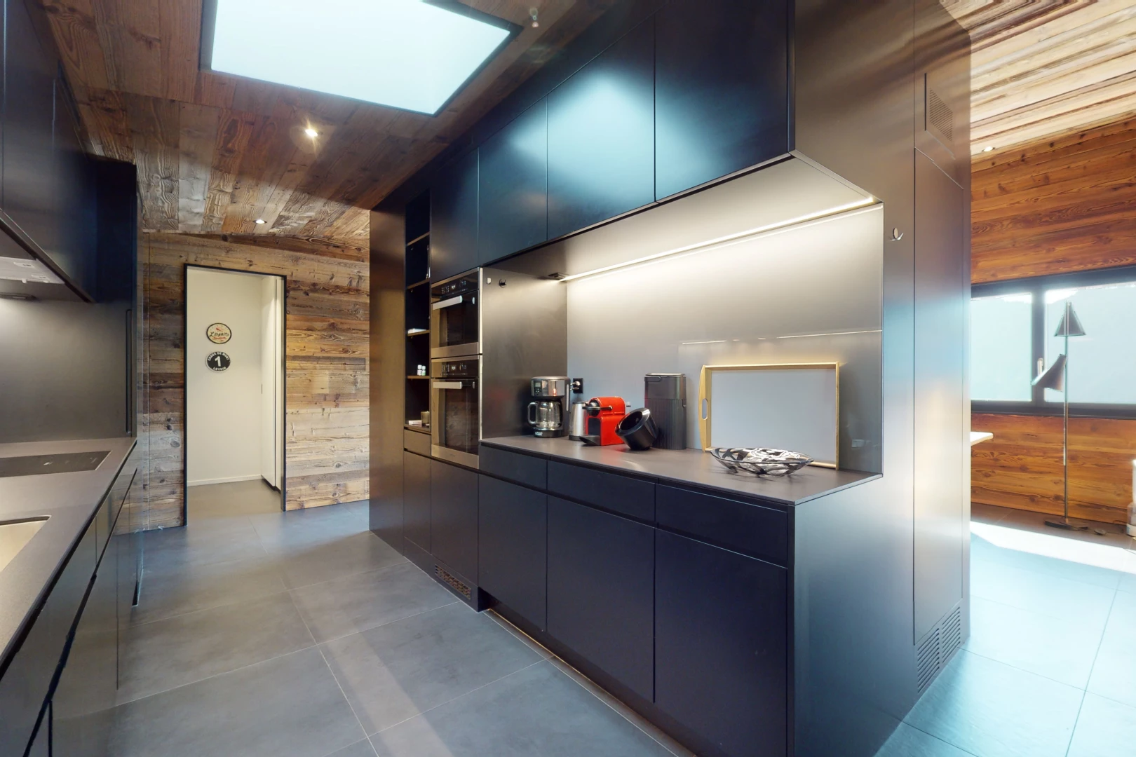 cuisine avec carrelage, meubles marron foncé, plafond de bois, four double, et mur en bois