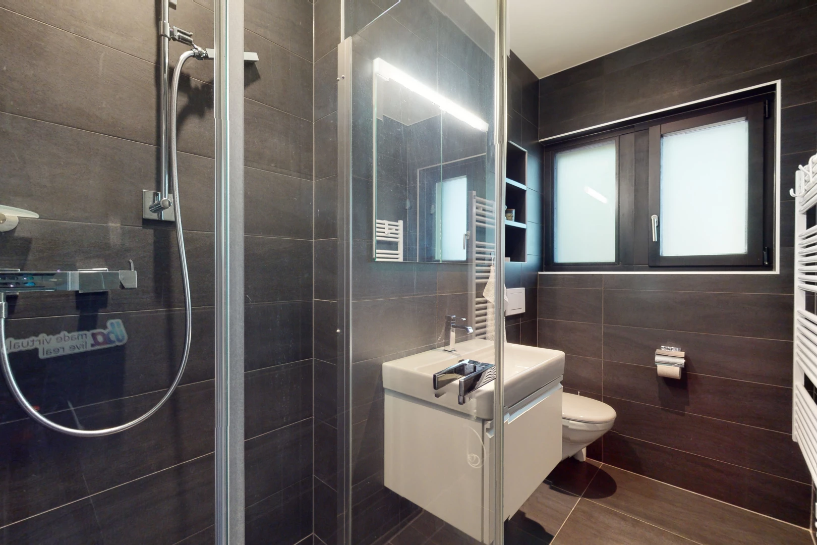 salle de bain avec carrelage, radiateur, toilettes, vasque, miroir, lumière naturelle, mur carrelé, meuble-lavabo, et douche