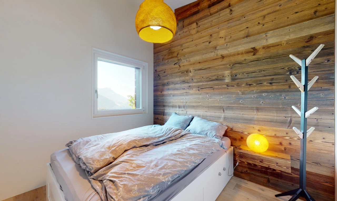 chambre avec plancher de bois, lumière naturelle, et mur en bois