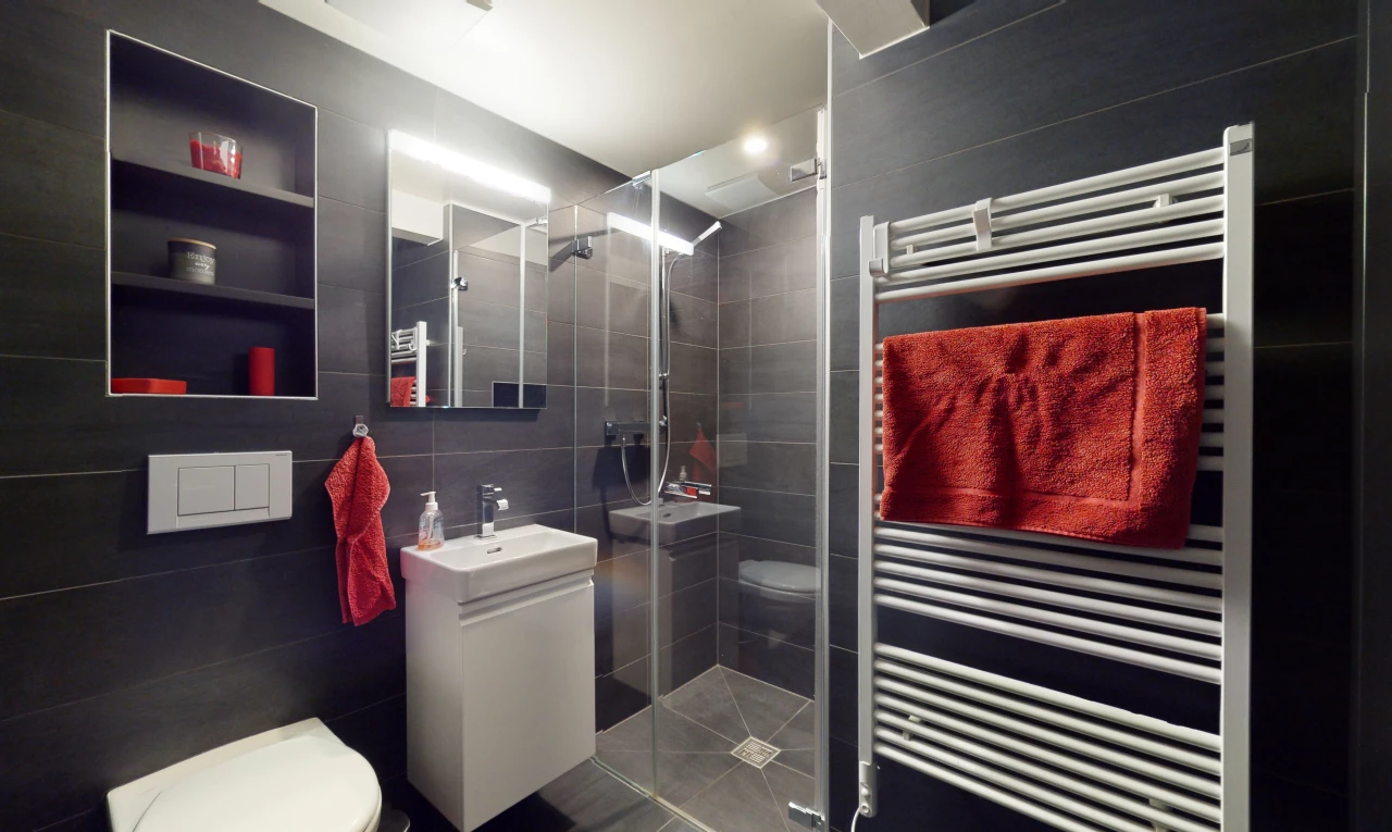 salle de bain avec radiateur, vasque, toilettes, miroir, mur carrelé, meuble-lavabo, et douche