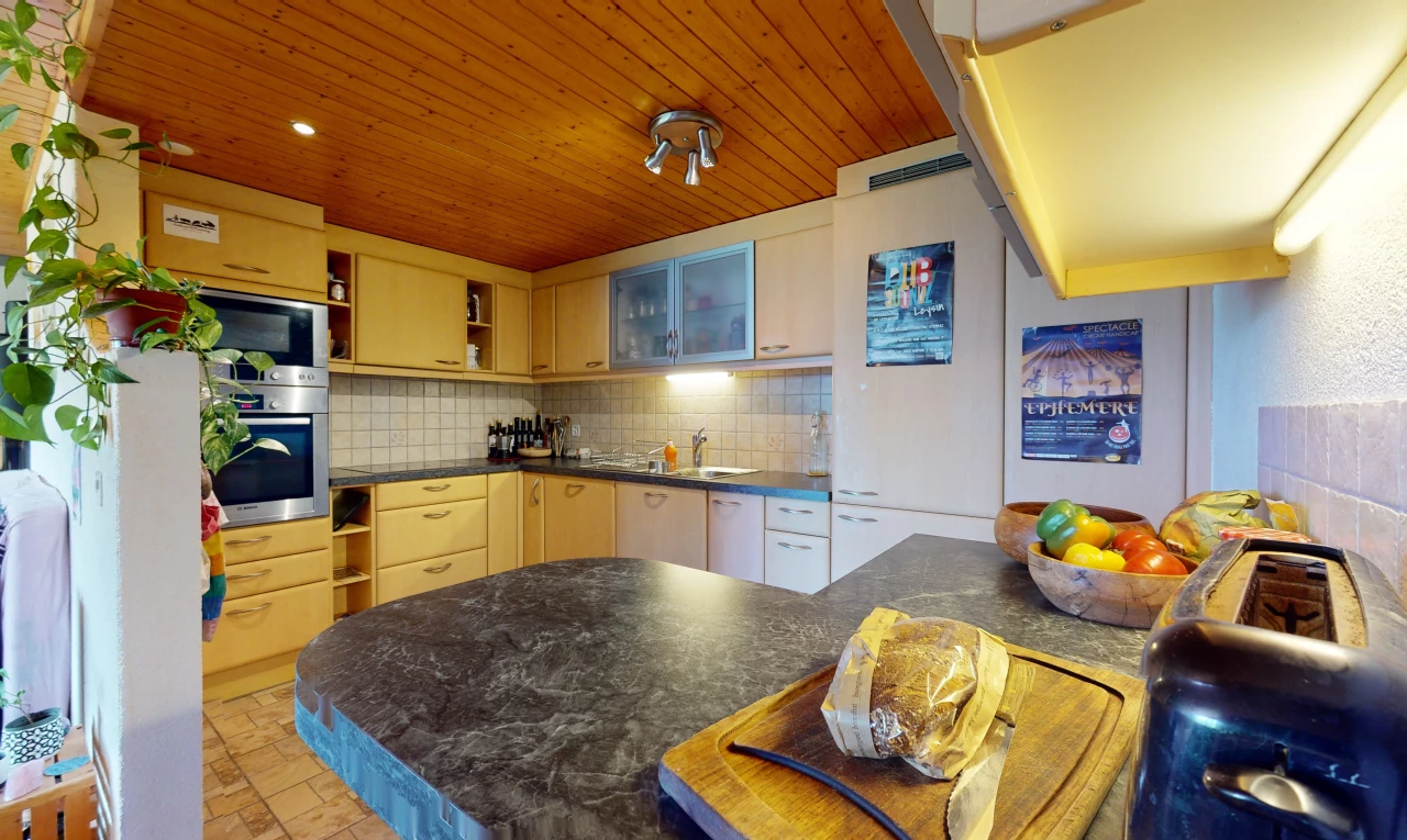 cuisine avec dosseret, meubles marron, carrelage, plan de travail, plafond de bois, et four