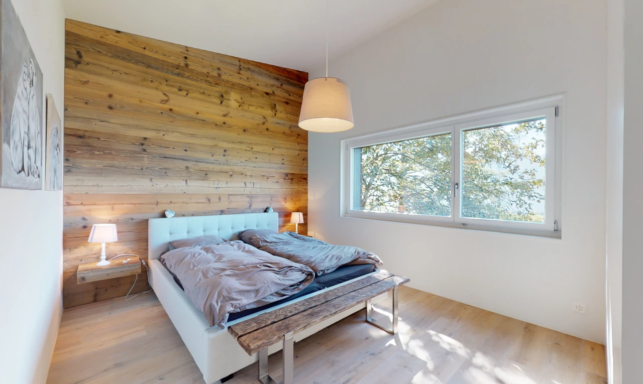 chambre avec plafond voûté, haut plafond, lumière naturelle, plancher de bois, et mur en bois