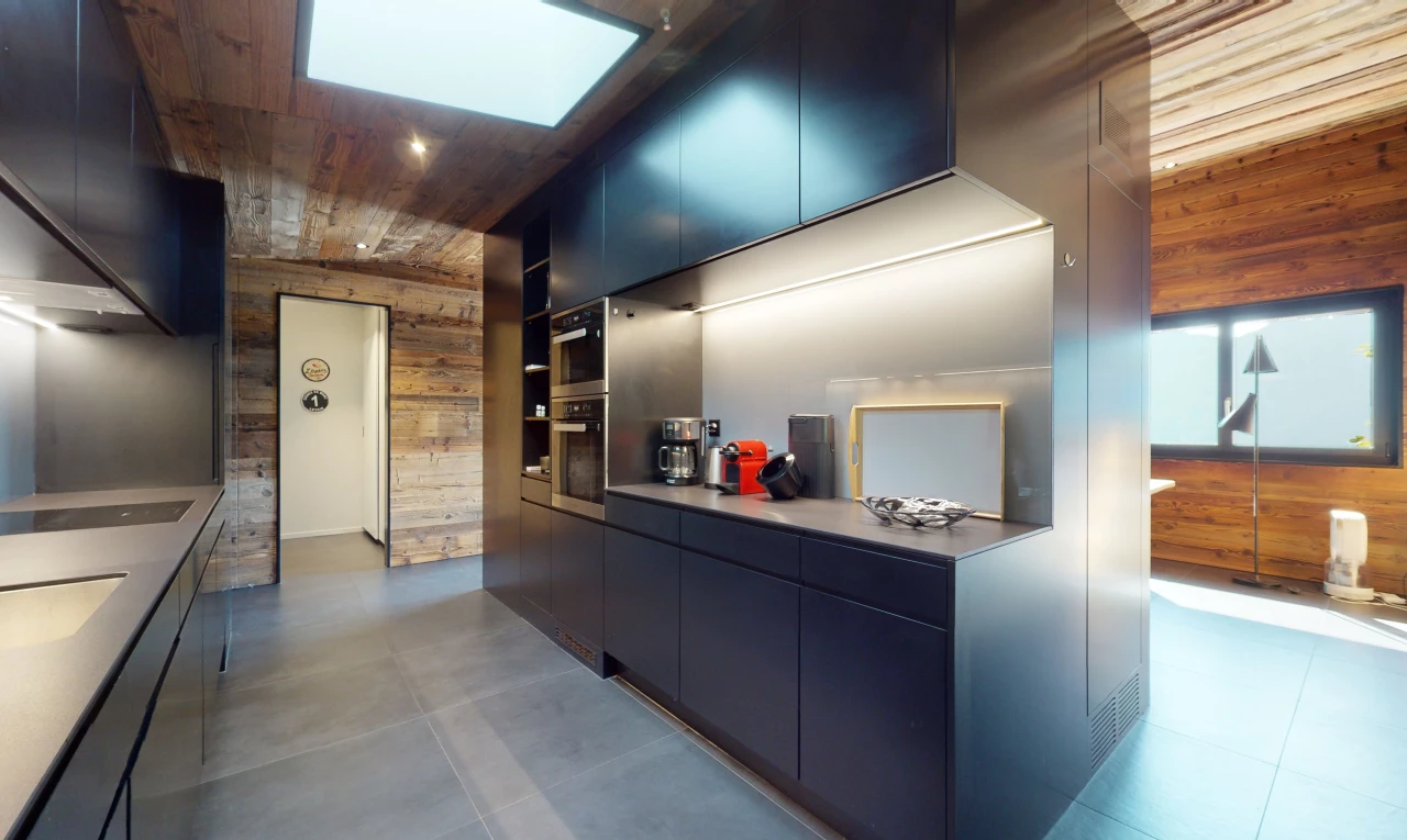 cuisine avec carrelage, meubles marron foncé, plafond de bois, four double, et mur en bois
