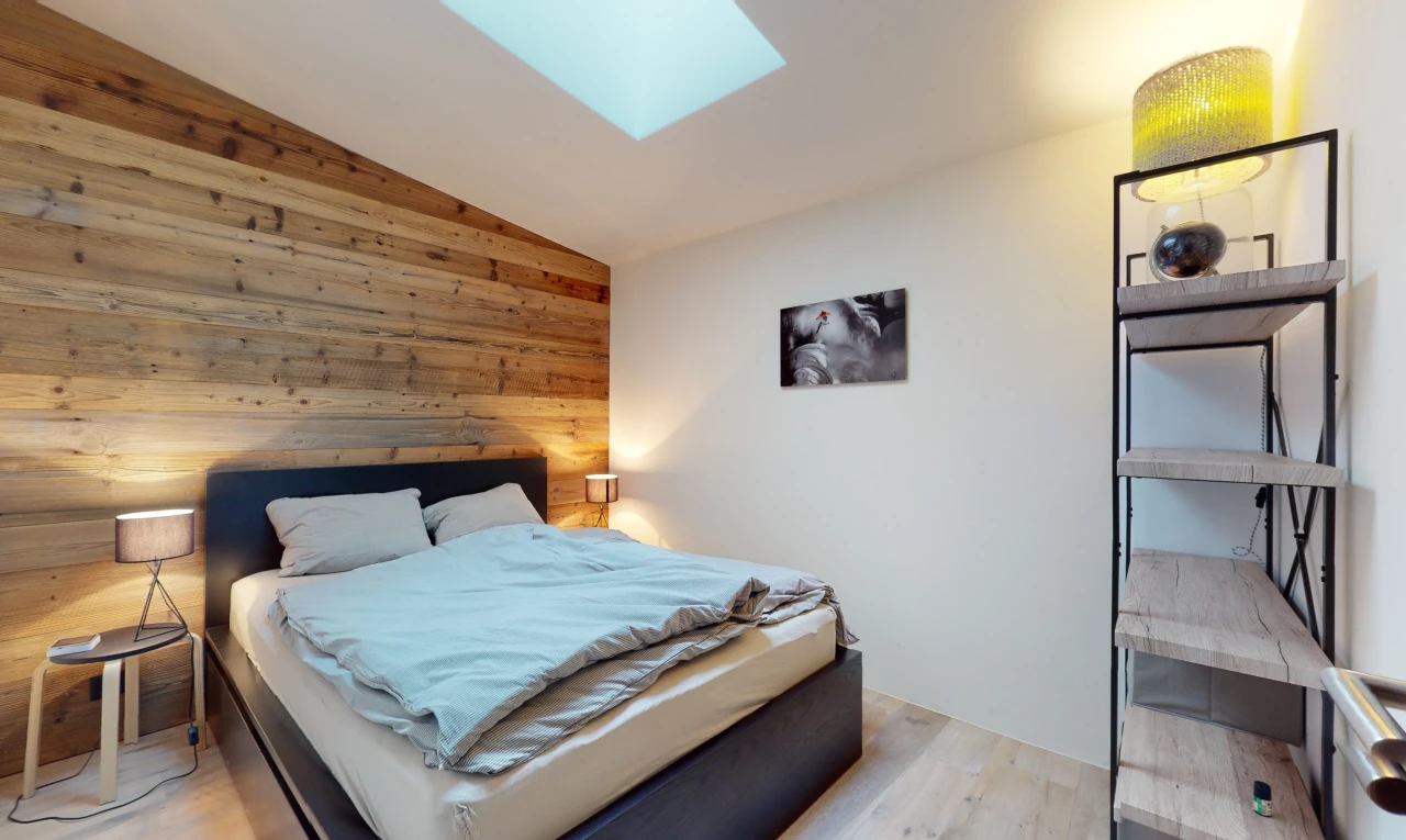 chambre avec plancher de bois, mur en bois, lucarne, et plafond voûté