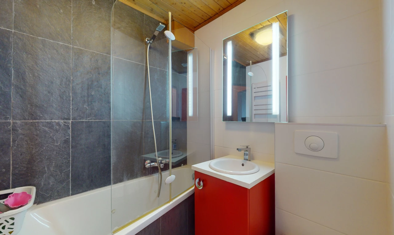 salle de bain avec meuble-lavabo, miroir, vasque, lumière naturelle, bain-douche, et plafond de bois
