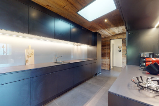 cuisine avec plafond voûté, carrelage, meubles marron foncé, plan de travail, plafond de bois, et lucarne