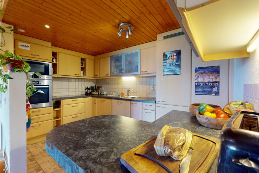 cuisine avec dosseret, meubles marron, carrelage, plan de travail, plafond de bois, et four