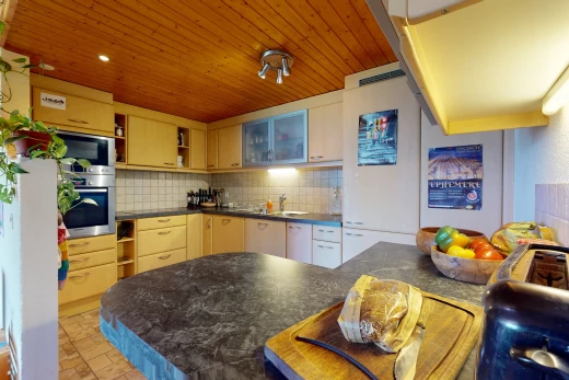 cuisine avec dosseret, meubles marron, carrelage, plan de travail, plafond de bois, et four