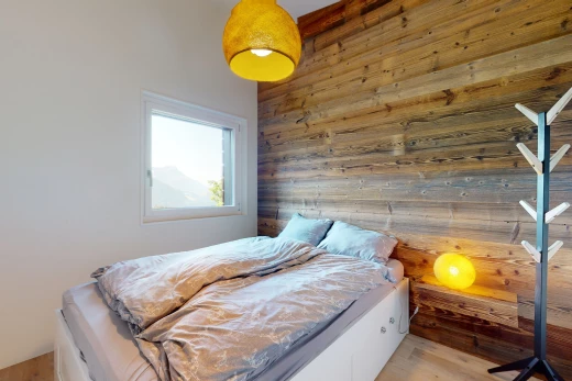 chambre avec plancher de bois, lumière naturelle, et mur en bois