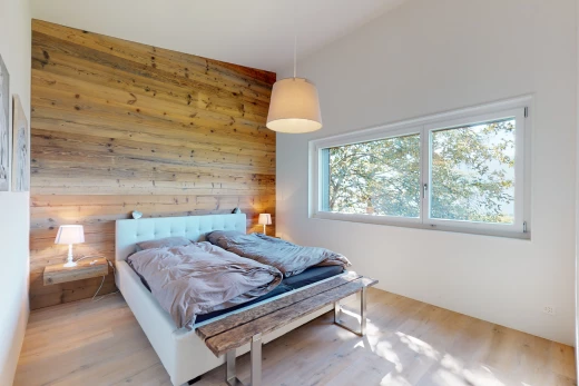 chambre avec plafond voûté, haut plafond, lumière naturelle, plancher de bois, et mur en bois