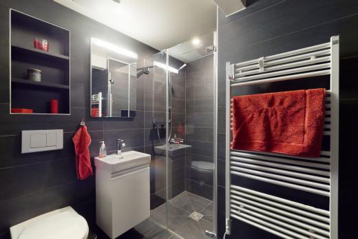 salle de bain avec radiateur, vasque, toilettes, miroir, mur carrelé, meuble-lavabo, et douche