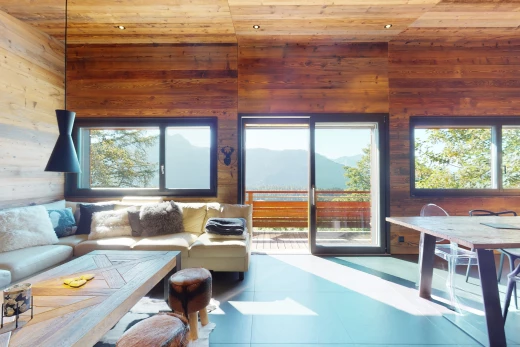 salon avec plafond voûté, carrelage, lumière naturelle, plafond de bois, et mur en bois