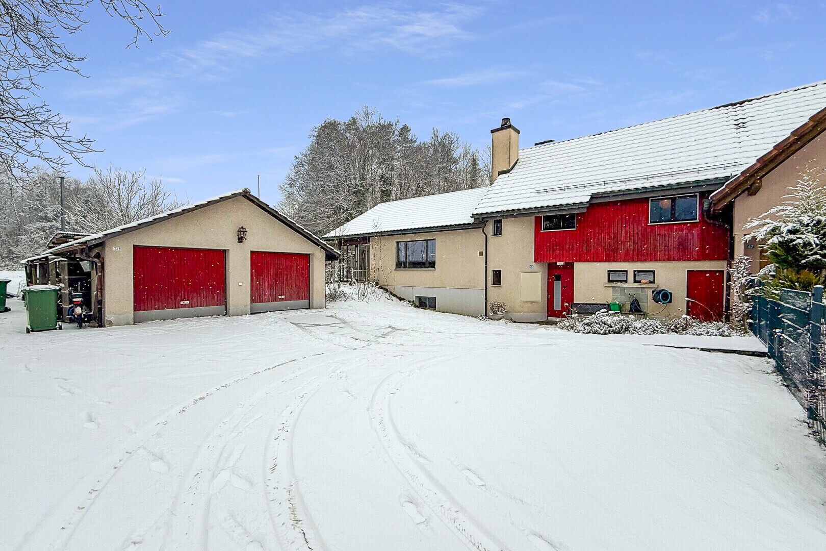 snow covered house featuring an outbuilding, a garage, and a chimney
