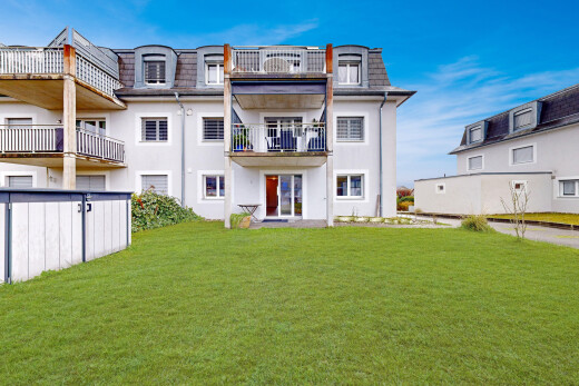 view of home with mansard roof, a yard, a balcony, and roof with shingles