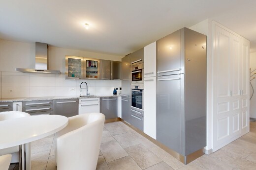 kitchen with wall chimney range hood, glass insert cabinets, tasteful backsplash, appliances with stainless steel finishes, and gray cabinetry