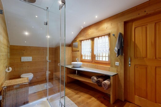 salle de bains avec wood wall, mur en bois, vaulted ceiling, plafond voûté, et lavabo (ou coiffeuse selon le contexte)