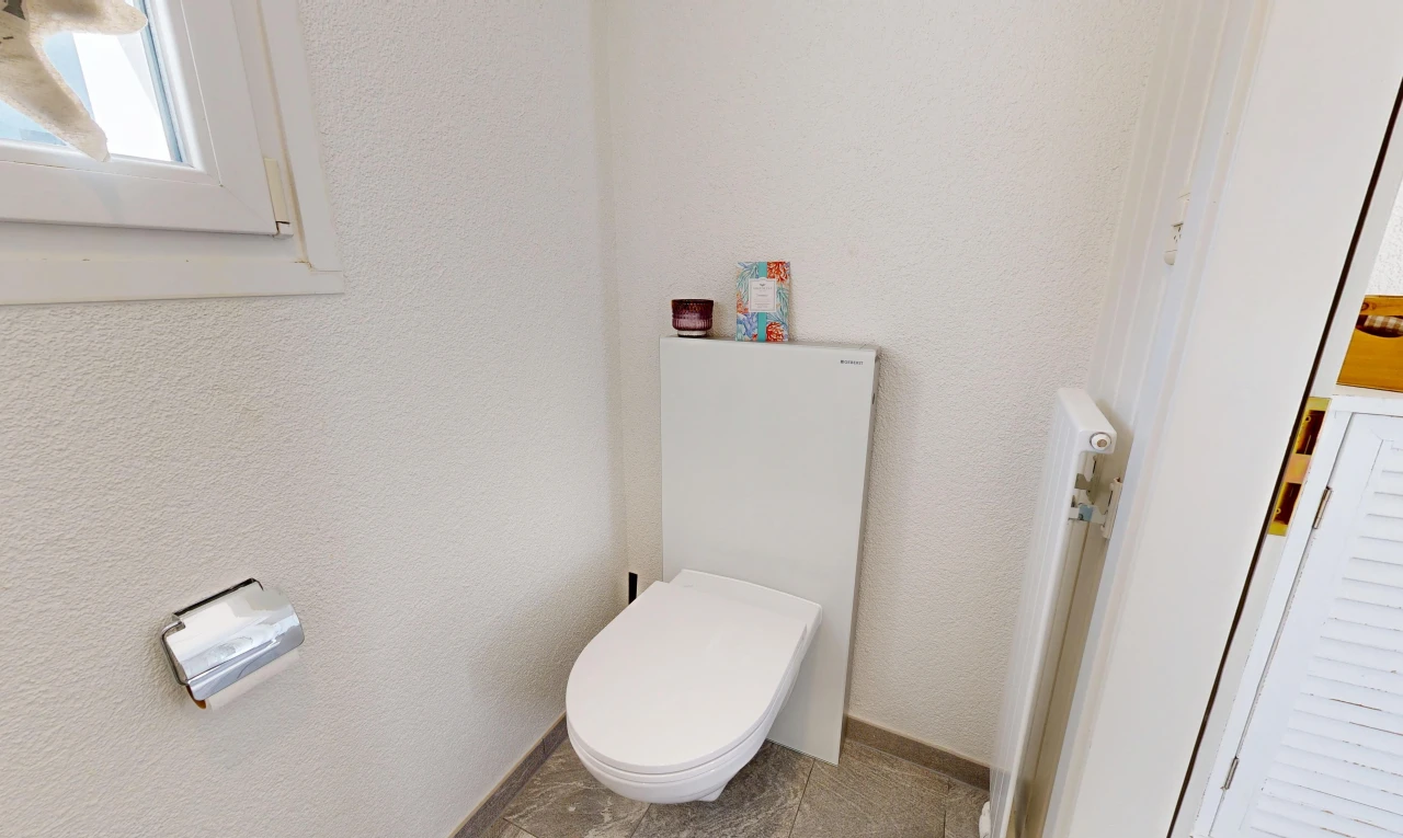 bathroom with toilet and a textured wall