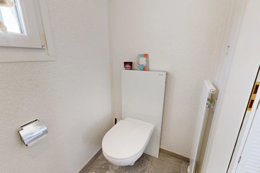 bathroom with toilet and a textured wall