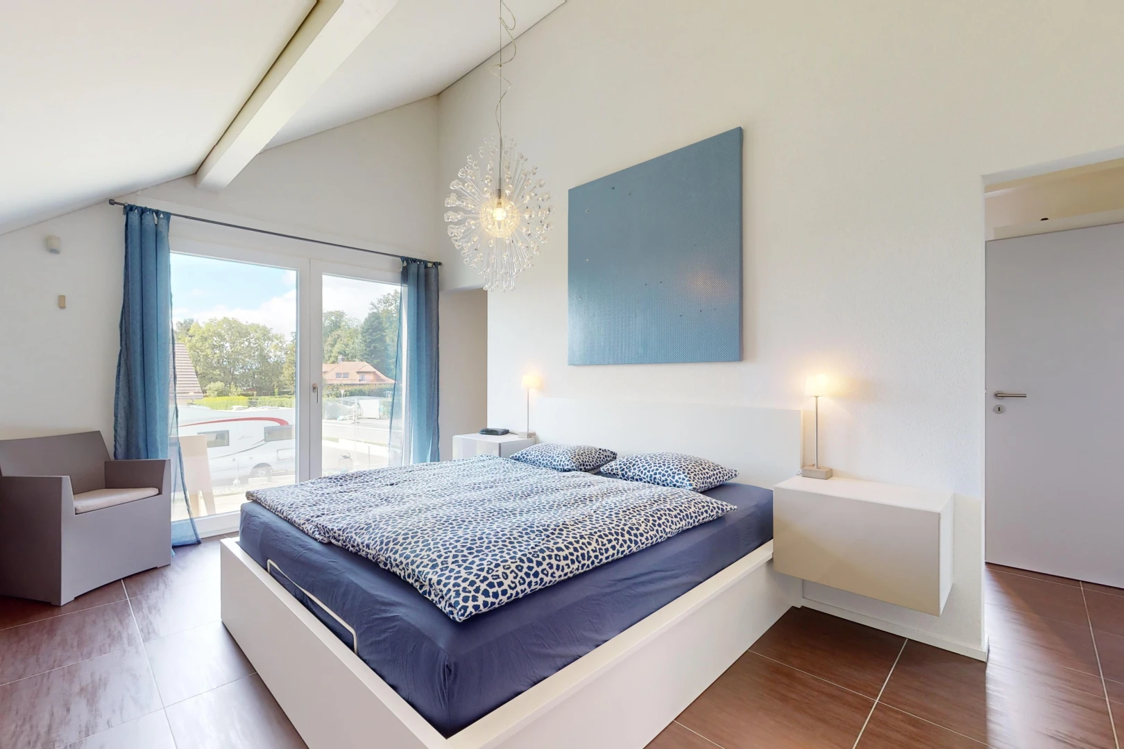 chambre avec plancher de bois, lumière naturelle, plafond voûté, et poutres apparentes