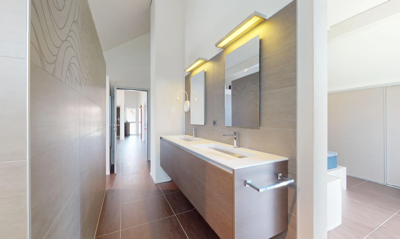 salle de bains avec miroir, plafond voûté, haut plafond, meuble-lavabo, et mur carrelé
