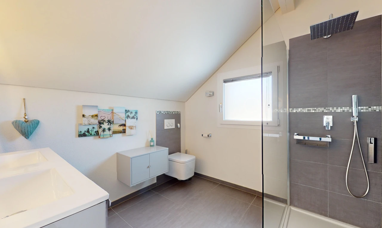 salle de bains avec toilettes, plafond voûté, meuble-lavabo, lumière naturelle, et douche